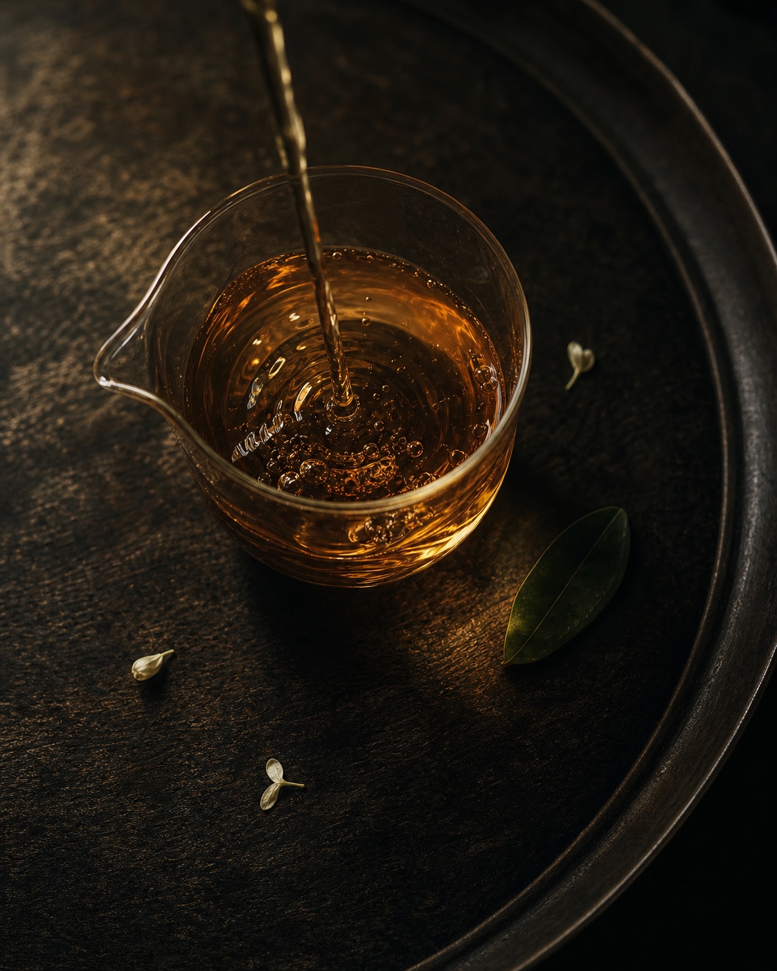 俯拍透明茶海注入琥珀茶汤、花瓣与绿叶的原创季节茶画面，代表四时花信方向